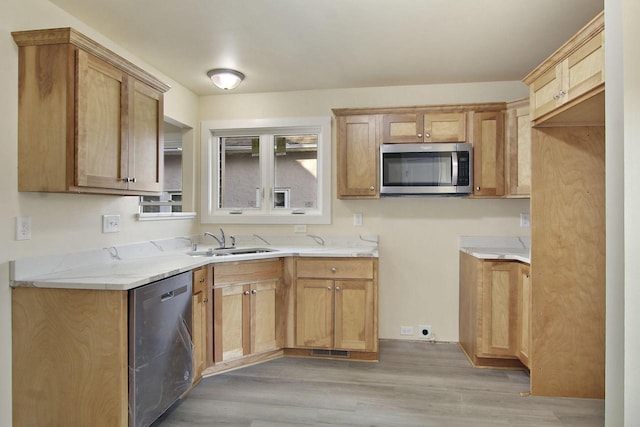 kitchen featuring light stone countertops, appliances with stainless steel finishes, light wood-type flooring, and sink