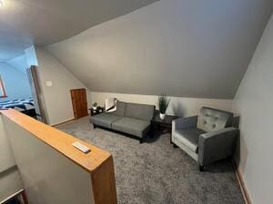 interior space with dark colored carpet and lofted ceiling