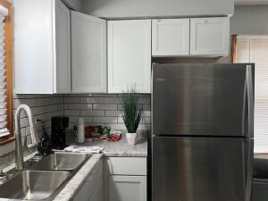 kitchen featuring white cabinets, backsplash, stainless steel fridge, and sink