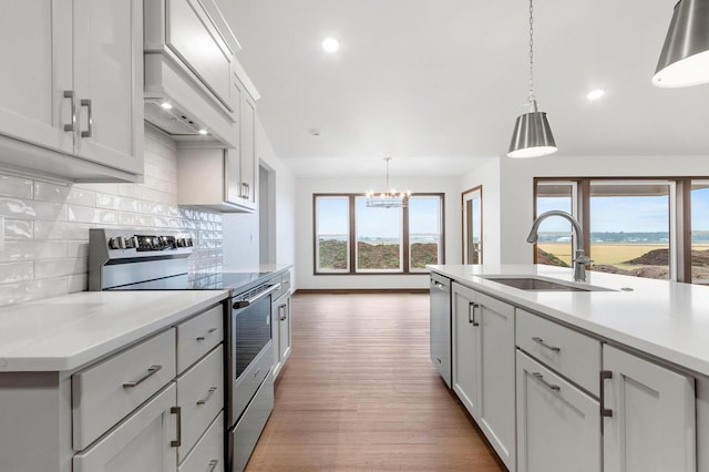 kitchen featuring sink, plenty of natural light, pendant lighting, appliances with stainless steel finishes, and light wood-type flooring