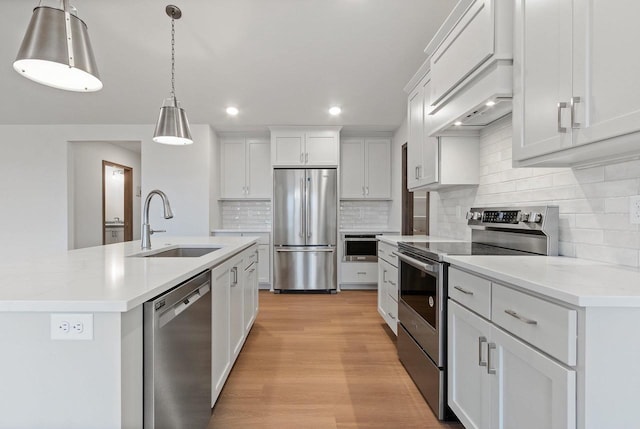 kitchen with white cabinetry, sink, hanging light fixtures, stainless steel appliances, and tasteful backsplash