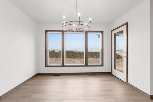 unfurnished dining area featuring light wood-type flooring and an inviting chandelier