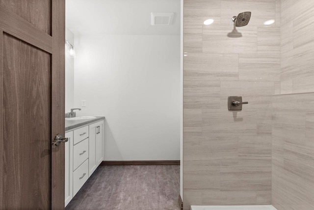 bathroom featuring hardwood / wood-style flooring, vanity, and tiled shower