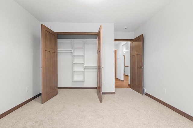 unfurnished bedroom featuring light colored carpet and a closet