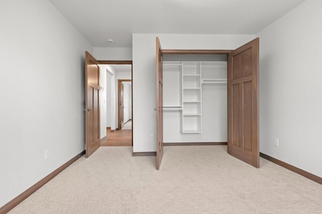 unfurnished bedroom featuring light carpet and a closet