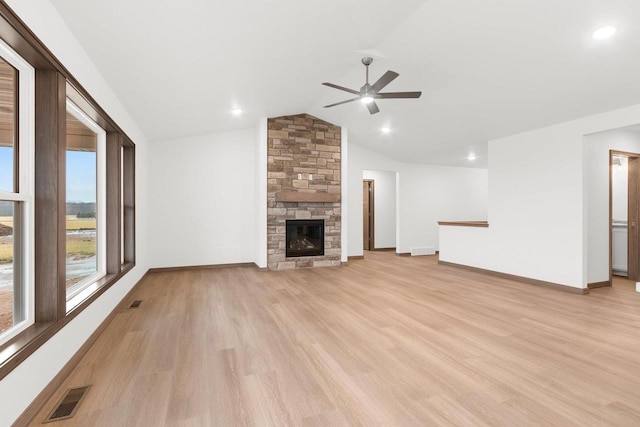 unfurnished living room featuring light hardwood / wood-style floors, vaulted ceiling, ceiling fan, and a stone fireplace