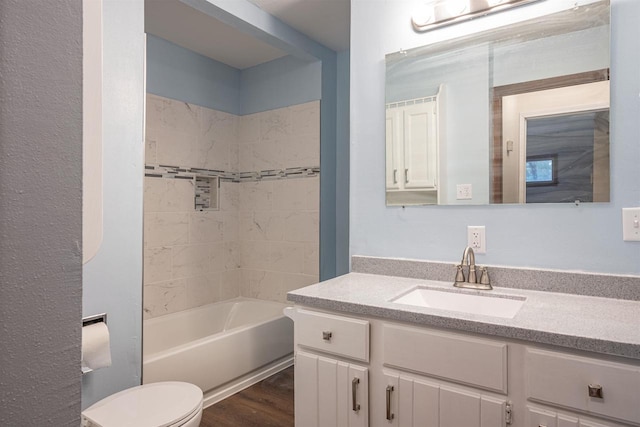 full bathroom with hardwood / wood-style floors, vanity, tiled shower / bath combo, and toilet