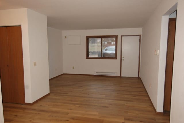 empty room with hardwood / wood-style floors and a baseboard radiator