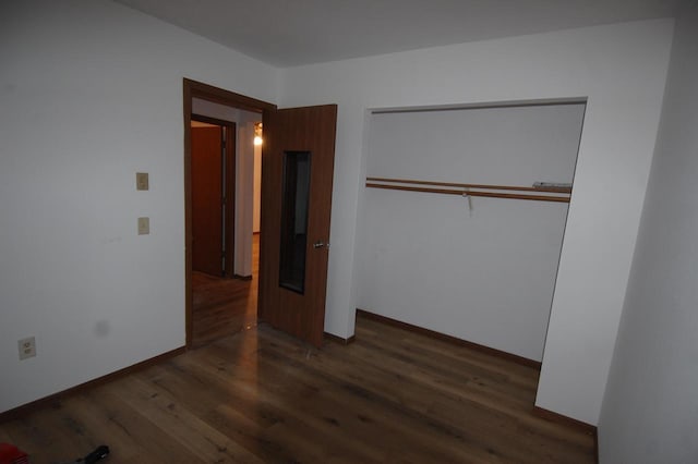 unfurnished bedroom featuring a closet and dark wood-type flooring