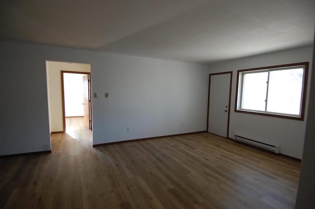 spare room featuring a baseboard radiator and dark hardwood / wood-style floors