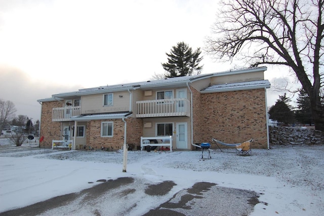 snow covered back of property with a balcony