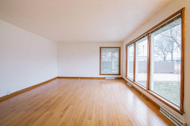 empty room with a textured ceiling and light hardwood / wood-style floors