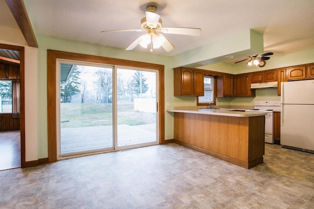 kitchen with a textured ceiling, ceiling fan, white appliances, and kitchen peninsula