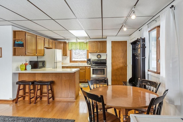 kitchen featuring light hardwood / wood-style flooring, kitchen peninsula, white fridge, stainless steel electric stove, and a kitchen bar