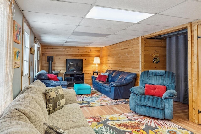 living room with wood-type flooring, a drop ceiling, and wood walls