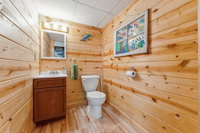 bathroom featuring hardwood / wood-style floors, vanity, a paneled ceiling, wooden walls, and toilet