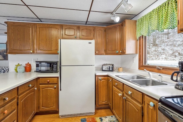 kitchen with sink, white fridge, track lighting, and light hardwood / wood-style flooring