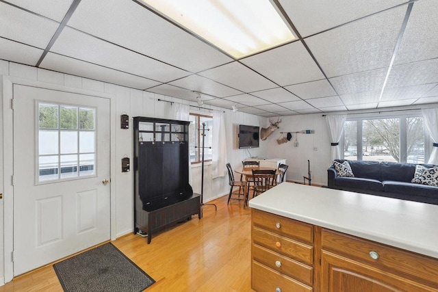 kitchen featuring a paneled ceiling, wooden walls, and light hardwood / wood-style floors