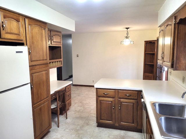 kitchen featuring decorative light fixtures, white fridge, kitchen peninsula, and sink