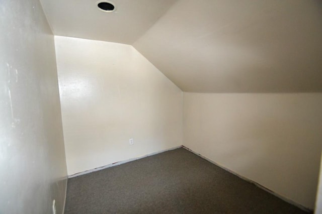 additional living space with dark carpet and vaulted ceiling