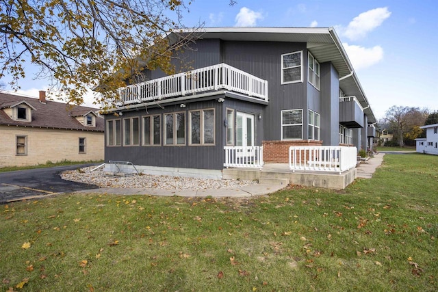 rear view of property featuring a lawn and a balcony