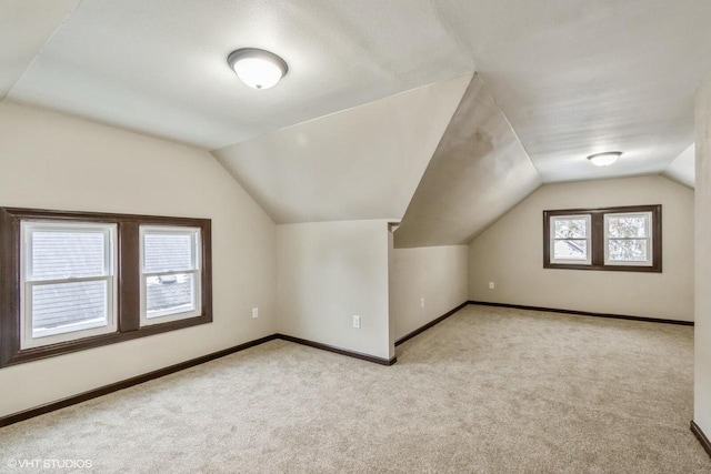 additional living space featuring light colored carpet and vaulted ceiling