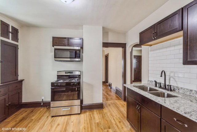 kitchen featuring light stone countertops, appliances with stainless steel finishes, light hardwood / wood-style flooring, and sink