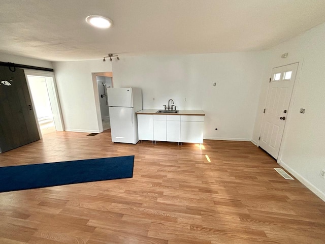 kitchen featuring sink, white fridge, and light wood-type flooring