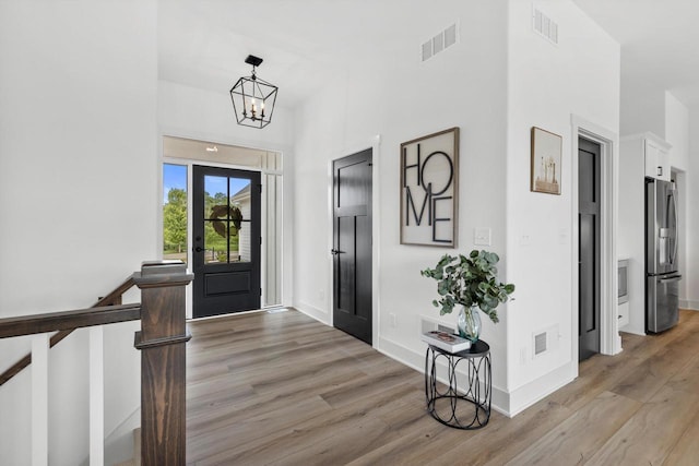 foyer entrance with a notable chandelier and light hardwood / wood-style floors