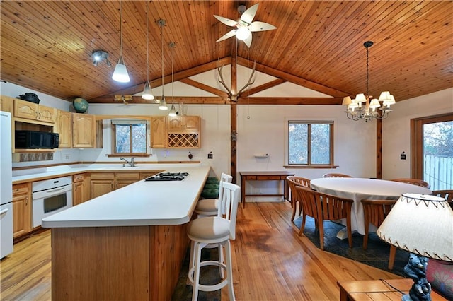 kitchen featuring a center island, light hardwood / wood-style flooring, lofted ceiling, decorative light fixtures, and white appliances