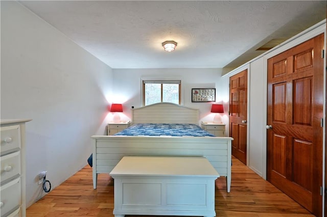 bedroom with a textured ceiling and light hardwood / wood-style flooring