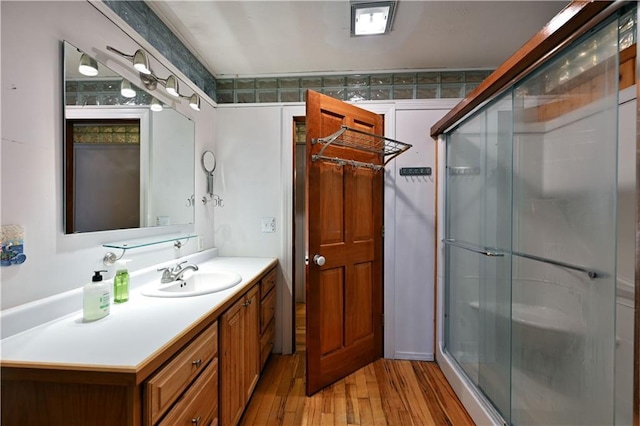 bathroom featuring hardwood / wood-style floors, vanity, and a shower with door