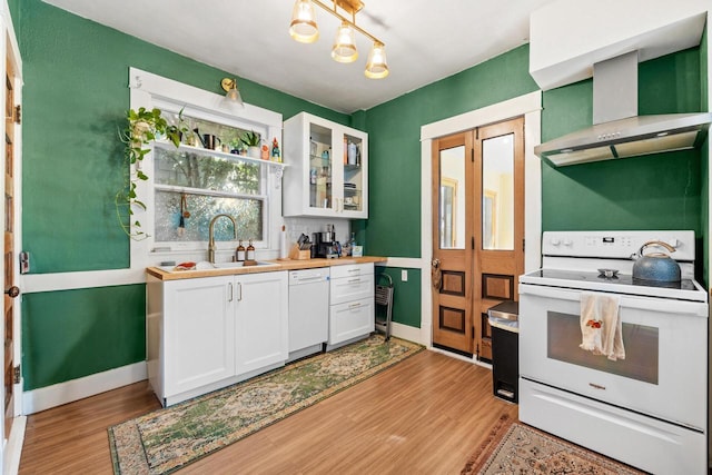 kitchen with white appliances, light hardwood / wood-style floors, white cabinetry, and wall chimney exhaust hood