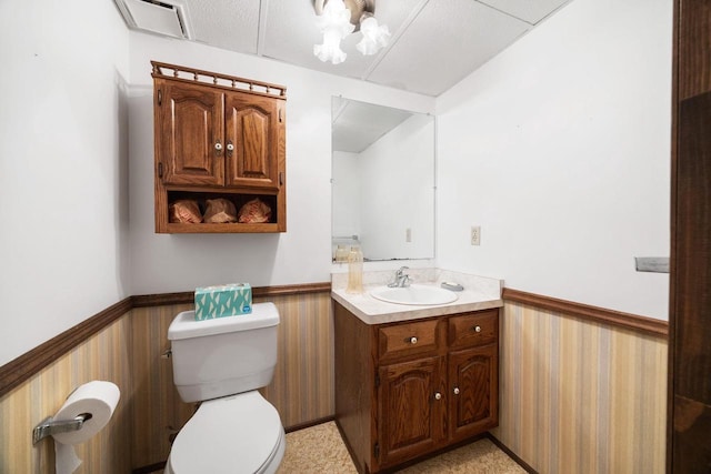 bathroom featuring vanity, wood walls, and toilet