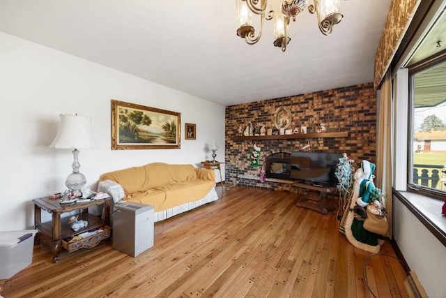 living room with wood-type flooring, an inviting chandelier, and brick wall