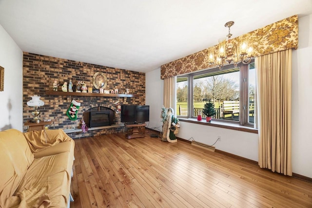 living room with a brick fireplace, an inviting chandelier, and hardwood / wood-style flooring