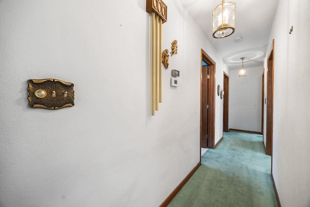 hall featuring light carpet and an inviting chandelier