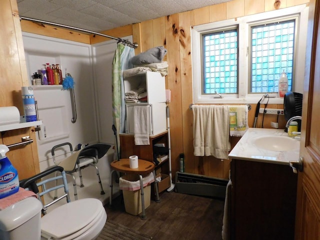 bathroom with curtained shower, a baseboard radiator, wood walls, vanity, and hardwood / wood-style flooring