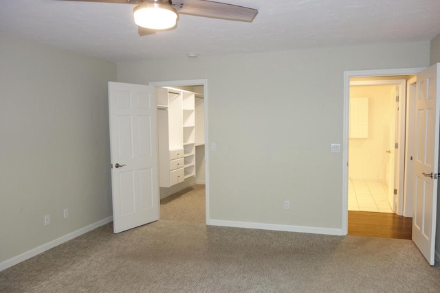 unfurnished bedroom with a walk in closet, light colored carpet, and a closet