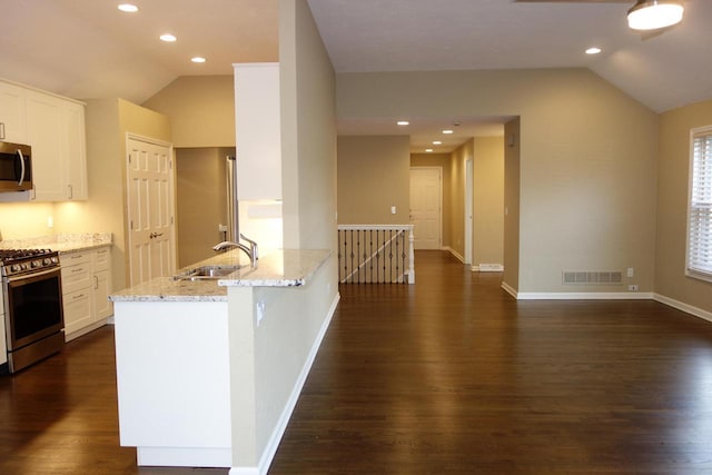 kitchen featuring kitchen peninsula, light stone countertops, stainless steel appliances, sink, and white cabinetry