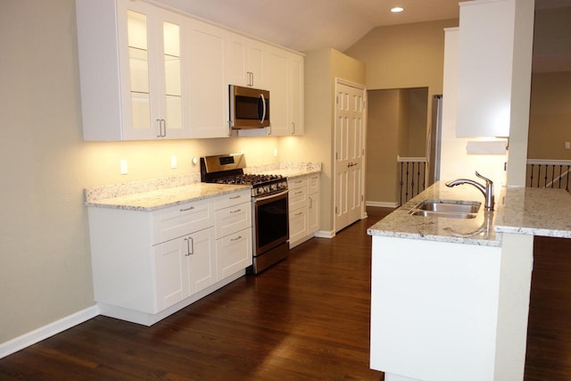 kitchen featuring sink, vaulted ceiling, appliances with stainless steel finishes, white cabinetry, and kitchen peninsula