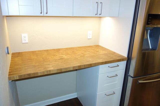 kitchen with butcher block countertops, white cabinetry, and stainless steel refrigerator with ice dispenser