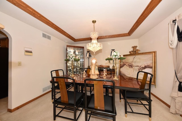 dining area with a notable chandelier, ornamental molding, light carpet, and a tray ceiling