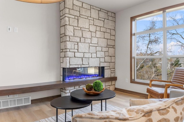 living room featuring light hardwood / wood-style flooring, a fireplace, and plenty of natural light