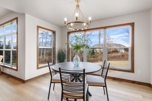 dining area with plenty of natural light, light wood-type flooring, and an inviting chandelier