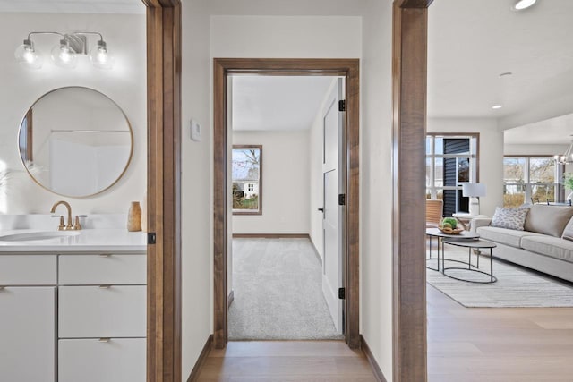 hall with sink, an inviting chandelier, and light hardwood / wood-style floors