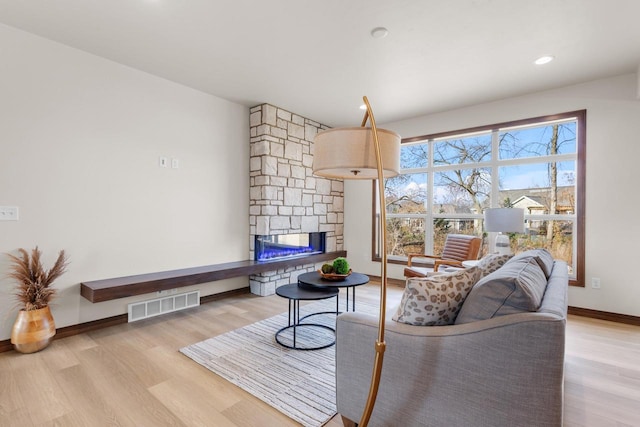 living room with light hardwood / wood-style flooring and a stone fireplace