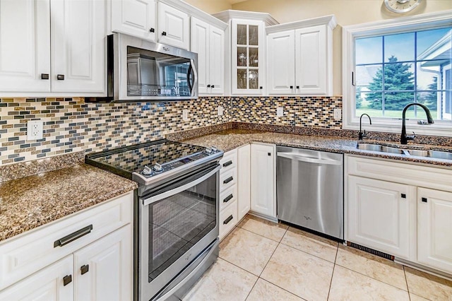 kitchen featuring sink, light tile patterned floors, appliances with stainless steel finishes, white cabinetry, and backsplash