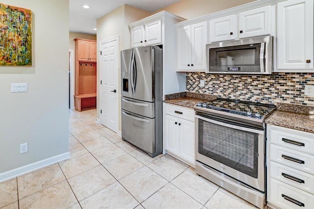 kitchen featuring light tile patterned flooring, appliances with stainless steel finishes, tasteful backsplash, white cabinets, and dark stone counters