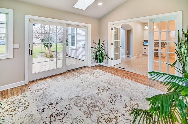 doorway to outside featuring light hardwood / wood-style flooring, vaulted ceiling with skylight, and french doors